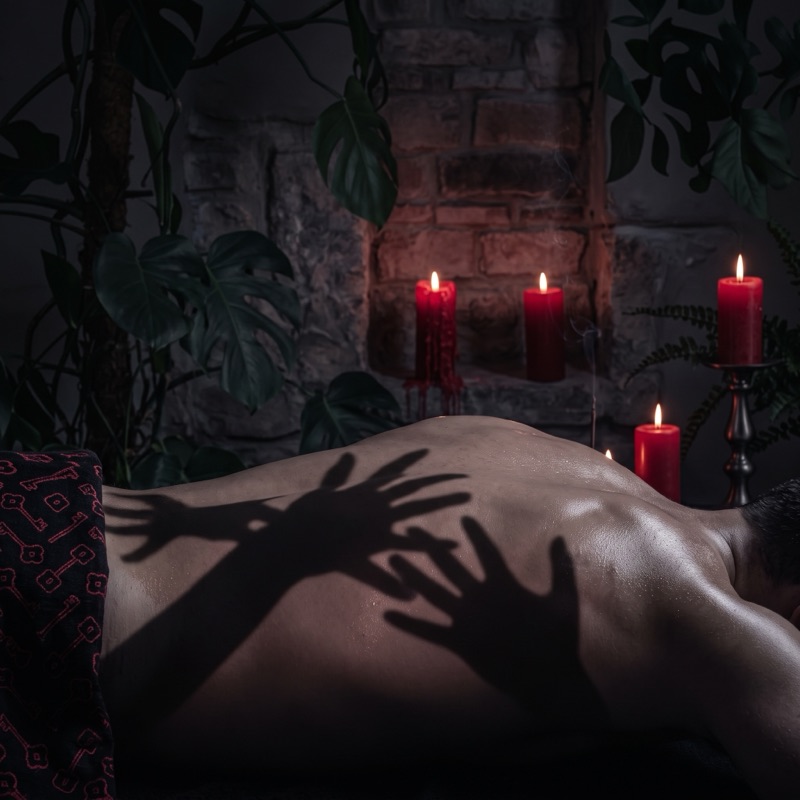 Sombras de manos sobre una espalda a la luz de las velas